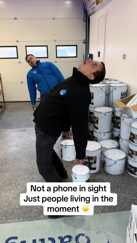 TikTok video cover: two of the crew larking about beside stacked coating tubs in the warehouse
